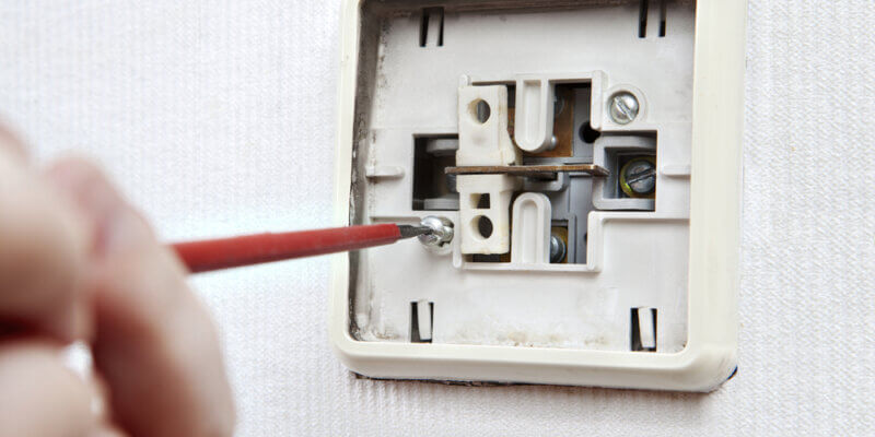 An electrician removing an old light switch